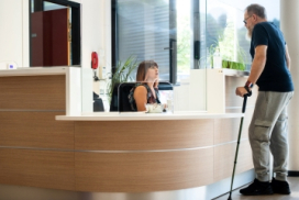 Photo illustrant une personne en situation de handicap s'adressant au comptoir d'accueil d'une MDPH