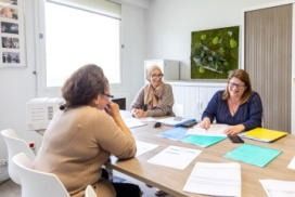 photo montrant trois femmes autour d'une table de réunion, dans un bureau de service à domicile